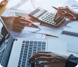 Persona revisando documentos con calculadora, área de contabilidad tributaria